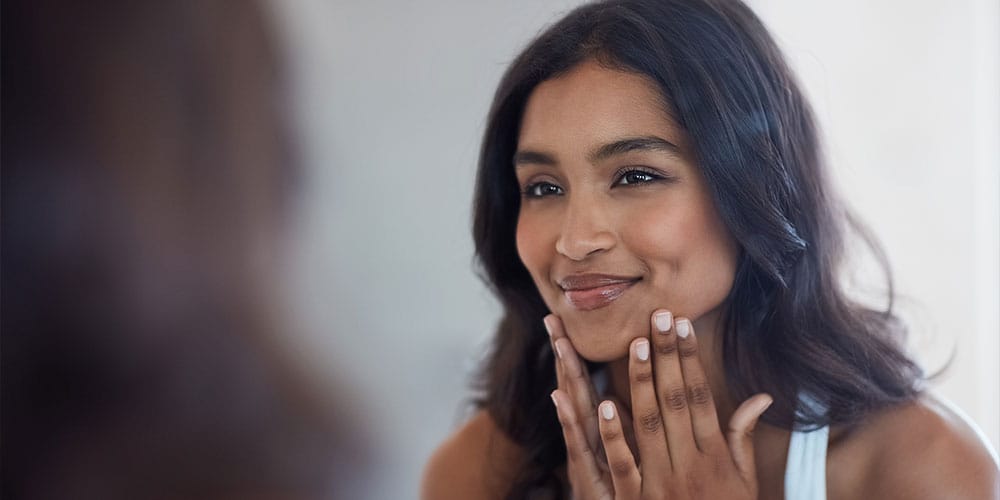 woman in Denver looking in the mirror after her chemical peel