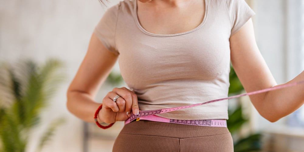 woman in Denver measuring her waist after taking semaglutide